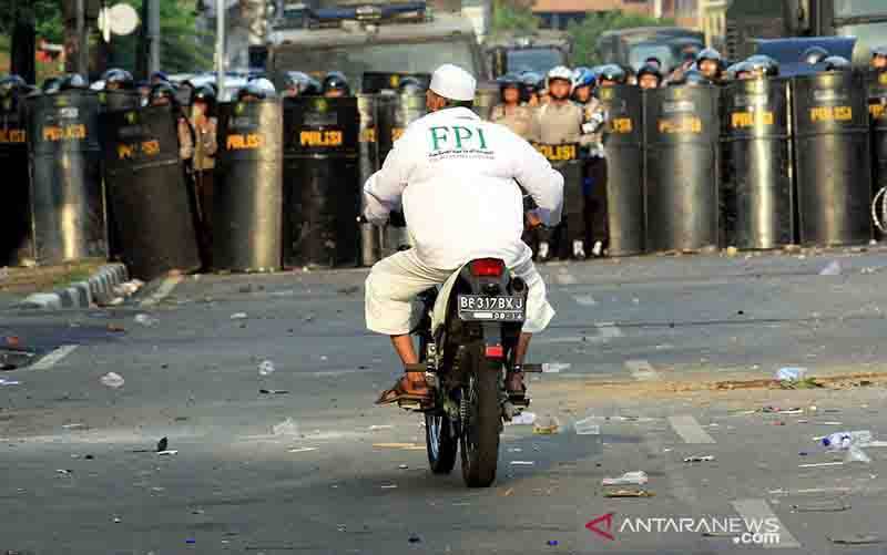 Seorang peserta aksi dari Front Pembela Islam (FPI) mengendarai motor di antara penjagaan aparat kepolisian saat aksi demo memprotes film 'Innocence of Muslims' di Kedutaan Amerika Serikat, Jakarta, Senin (17/9/2012). (foto : ANTARAFOTO/DHONI SETIAWAN)