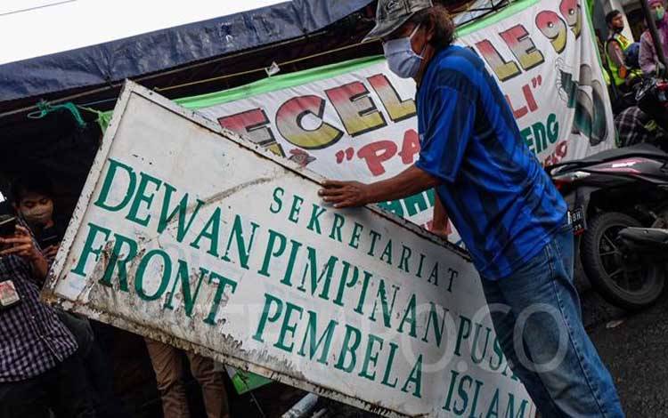 Plang Front Pembela Islam (FPI) dicopot pasca pemerintah resmi membubarkan FPI, di Petamburan, Jakarta, Rabu, 30 Desember 2020. Aparat kepolisian tampak mencopoti baliho bertuliskan FPI maupun yang bergambar Rizieq Shihab di kawasan Petamburan yang merupakan markas FPI. TEMPO/Hilman Fathurrahman W