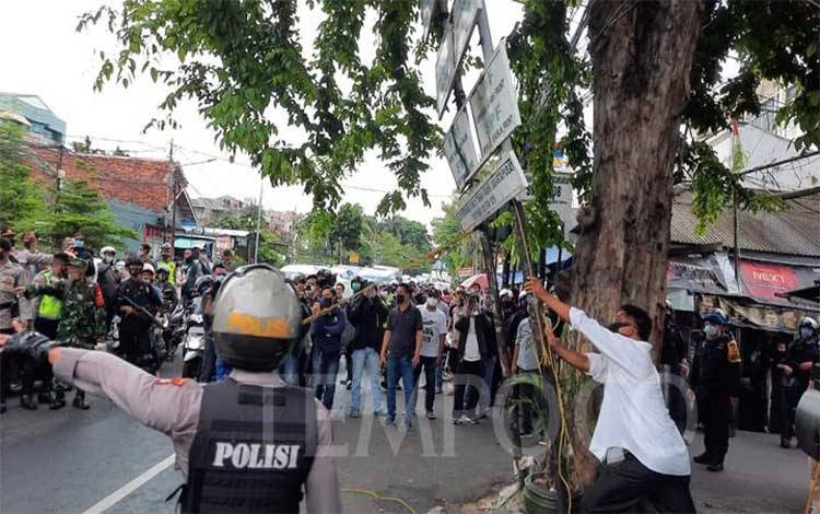 Polisi merobohkan plang Front Pembela Islam (FPI) di Petamburan, Jakarta, Rabu, 30 Desember 2020. Sejumlah aparat kepolisian yang membawa senjata laras lanjang dan pelontar gas air mata tampak berjaga di sekitar lokasi. TEMPO/M Yusuf Manurung