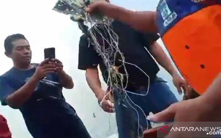 Petugas gabungan mengevakuasi serpihan kabel diduga milik pesawat Sriwajaya Air SJY 182 di Pulau Laki, Kepulauan Seribu, Sabtu (9/1/2021)