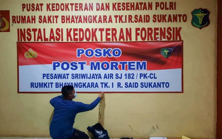 Petugas memasang spanduk Posko Post Mortem untuk mengidentifikasi korban pesawat Sriwijaya Air SJ-182 di Rumah Sakit Polri Kramatjati, Jakarta Timur, Minggu (10/1/2021). (ANTARA/Andi Firdaus)