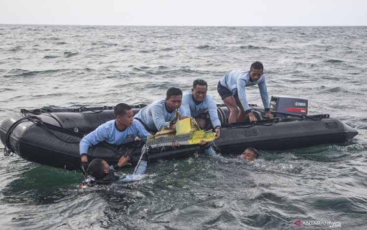 Sejumlah prajurit Satuan Komando Pasukan Katak (Satkopaska) Armada 1 berusaha mengangkat puing pesawat Sriwijaya Air SJ 182 dari dasar perairan Kepulauan Seribu, Jakarta, Senin (11/1/2021). Operasi pertolongan dan pencarian kecelakaan pesawat Sriwijaya Air SJ-182 pada hari ketiga difokuskan pada pencarian di bawah permukaan laut, baik untuk jenazah penumpang, serpihan potongan bagian pesawat terbang maupun kotak hitam