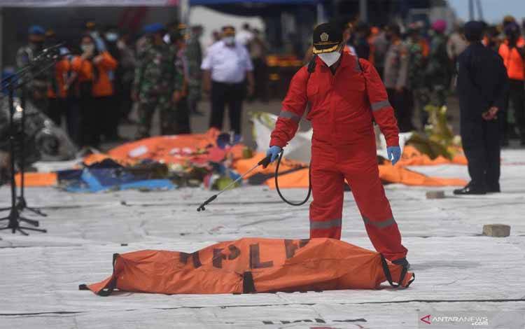 Petugas menyemprotkan disinfektan ke kantung jenazah korban pesawat Sriwijaya Air PK-CLC nomor penerbangan SJ 182 yang jatuh di perairan Pulau Seribu, di Dermaga JICT, Jakarta, Selasa (12/1/2021)
