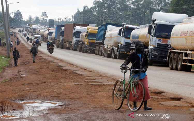 Seorang perempuan berjalan melewati truk-truk yang menunggu dalam antrian 10 kilometer untuk menyebrangi perbatasan Kenya-Uganda di kota Busia, Kenya, Sabtu (14/11/2020)