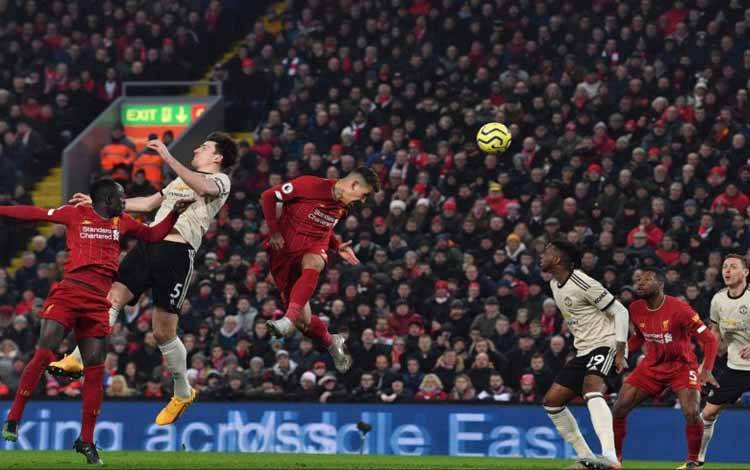 Pemain Liverpool Roberto Firmino memenangkan duel bola atas dengan Harry Maguire dalam pertandingan liga kedua tim di Stadion Anfield, Liverpool, 19 Januari 2020
