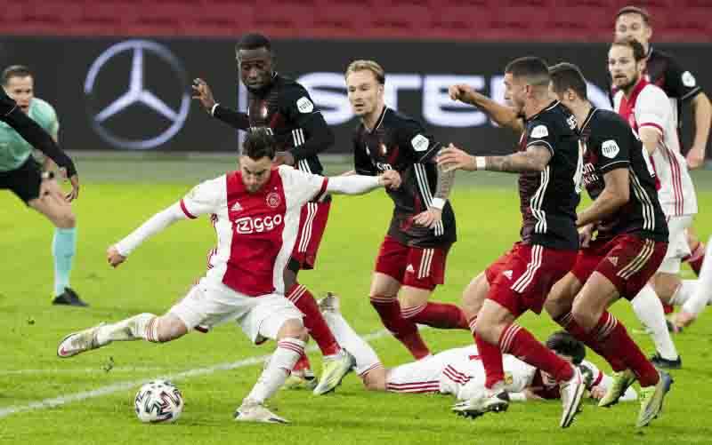 Pemain Ajax Nicolas Tagliafico saat melepaskan tendangan di antara hadangan bek Feyenoord kala keduanya bertemu dalam derbi De Klassieker, Minggu (17/1/2021). (foto : ANTARA/Pro Shots/Sipa USA via Reuters)