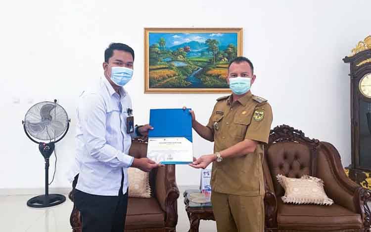 Plt Manajer PLN ULP Kuala Kurun Agung Darmawan menyerahkan penghargaan kepada Bupati Gumas Jaya S Monong 