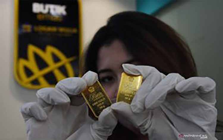  Karyawan menunjukan emas batangan yang dijual di Butik Emas Antam, Kebon Sirih, Jakarta