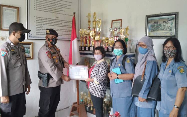 Kapolsek Bukit Batu Iptu Muludin menerima penghargaan dari Kepala SMPN 5 Palangka Raya, Elgawati