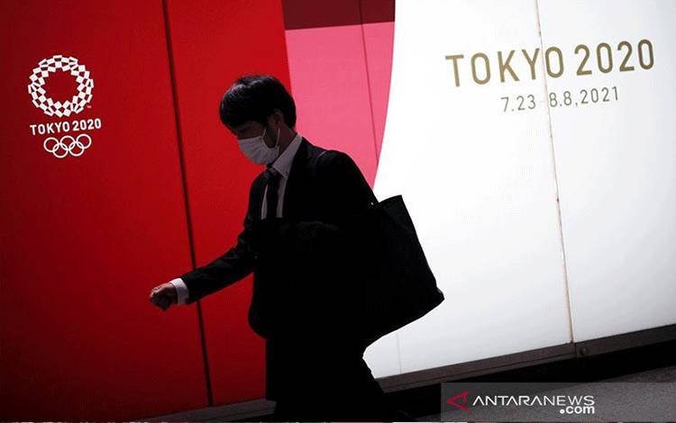 Seorang pria yang mengenakan masker pelindung berjalan melewati iklan Olimpiade Tokyo 2020 yang telah ditunda hingga 2021 karena wabah penyakit coronavirus (COVID-19), di Tokyo, Jepang, 22 Januari 2021. ANTARA/REUTERS / Issei Kato/pri. (REUTERS/ISSEI KATO)