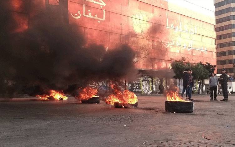 Demonstran berdiri di dekat ban yang terbakar di Tripoli, Lebanon, Senin (25/1/2021), selama protes terhadap penguncian dan kondisi ekonomi yang memburuk di tengah penyebaran virus corona (COVID-19). ANTARA FOTO/REUTERS/Walid Saleh/FOC/sa