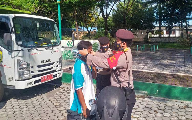 Wakil Direktur Samapta Polda Kalteng sekaligus sebagai Kasubsatgas Yustisi Covid-19, AKBP Timbul RK Siregar saat memasangkan masker kepada pengguna Jalan.