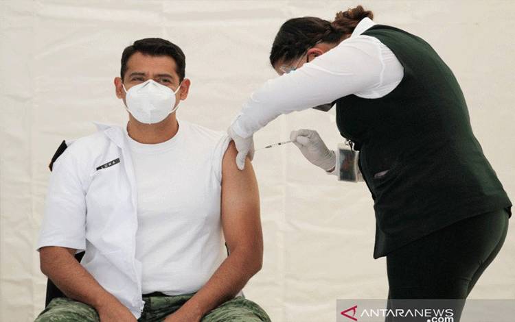 Seorang anggota staf medis menerima suntikan dosis vaksin Pfizer-BioNTech COVID-19 di barak militer di Saltillo, Meksiko, Senin (28/12/2020). REUTERS/Daniel Becerril/nz/cfo (REUTERS/DANIEL BECERRIL)