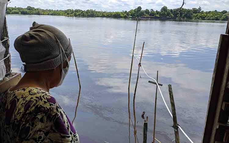 Seorang warga saat melihat kondisi Sungai Mentaya yang tervemar akibat tumpahan BBM dari sebuah kapal yang tambat di Pertamina