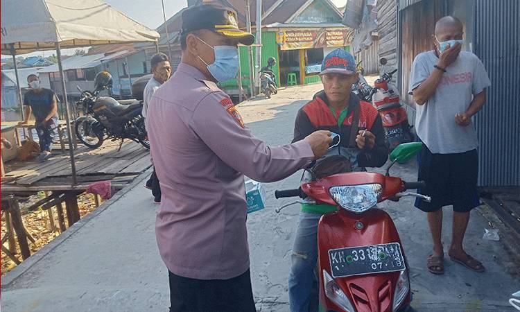 Kabagops Polresta Palangka Raya Kompol Hemat Siburian saat membagikan masker gratis kepada warga Puntun.