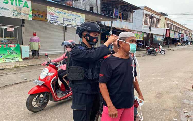 Personel Polda Kalteng saat memberikan masker gratis sekaligus memasangkan kepada warga