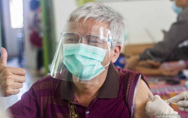 Seorang warga lansia (lanjut usia) mengangkat jempol saat menjalani penyuntikkan vaksin COVID-19