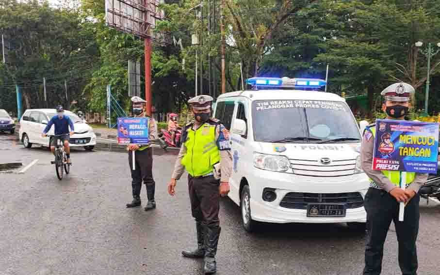 Anggota Satlantas Polresta Palangka Raya saat mengatur arus lalu lintas sembari menyosialisasikan Prokes dengan papan portable dan pengeras suara kepada pengguna jalan.