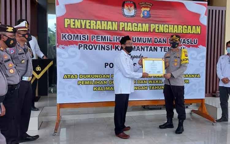 Ketua KPU Seruyan Agus Sukron Ma'mun menyerahkan piagam penghargaan yang diterima Kapolres Seruyan AKBP Bayu Wicaksono