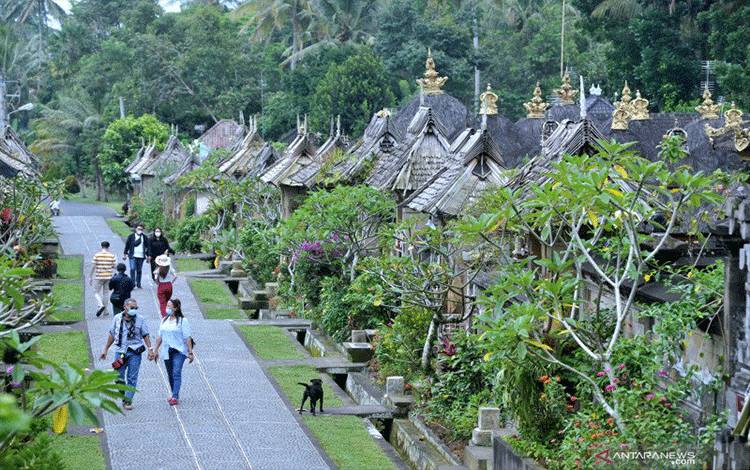 Wisatawan berjalan di sekitar deretan rumah tradisional di Desa Wisata Penglipuran, Bangli, Bali, Jumat (26/2/2021). ANTARA FOTO/Fikri Yusuf/wsj.