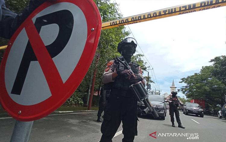 Petugas kepolisian berjaga di lokasi ledakan bom di depan Gereja Katedral Makassar, Sulawesi Selatan, Minggu (28/3/2021). (ANTARA FOTO/Abriawan Abhe/wpa/foc)