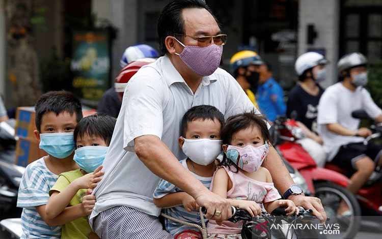Seorang pria mengendarai sepeda membawa anak-anaknya melewati sebuah jalan ditengah mewabahnya virus corona (COVID-19), di Hanoi, Vietnam