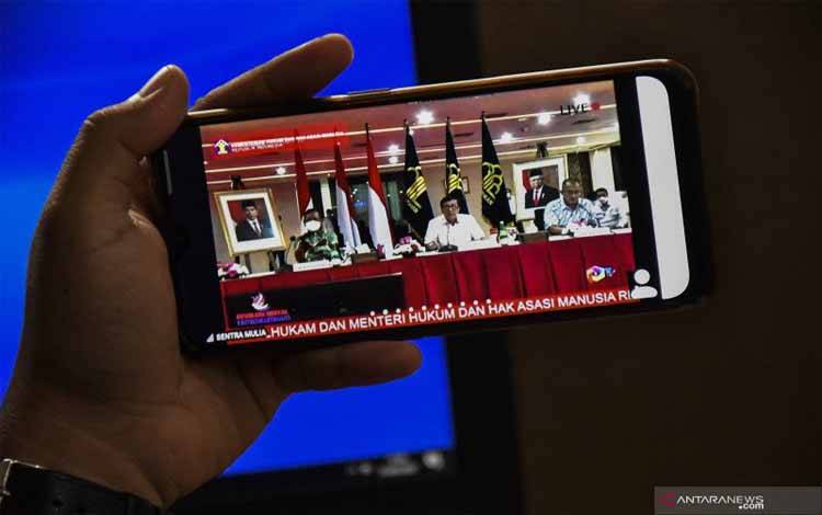 Jurnalis mengamati layar telepon pintar konferensi pers dari Kementerian Hukum dan HAM terkait kepengurusan Partai Demokrat yang digelar secara virtual di Jakarta, Rabu (31/3/2021)