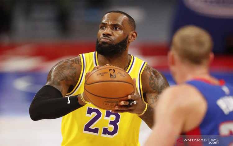 Pebasket Los Angeles Lakers LeBron James (kiri) bersiap melempar bola dan dijaga oleh pebasket Detroit Pistons Mason Plumlee (kanan) dalam laga lanjutan NBA, di Little Caesars Arena, Detroit, Michigan, Amerika Serikat, Kamis (28/1/2021)