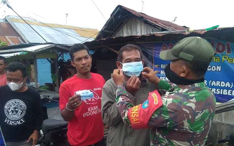 Serma Yulianto, Babinsa Kelurahan Pahandut Kodim 1016/Palangka Raya melaksanakan sosialisasi prokes dan membagikan masker.