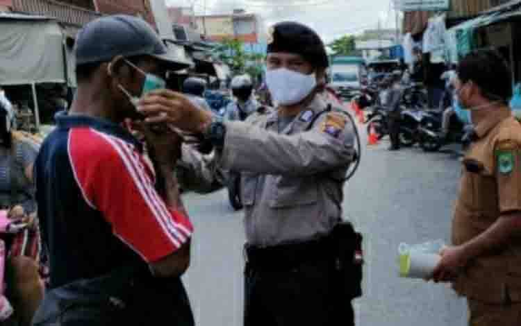 Petugas gabungan dari Posko PPKM Mikro Kelurahan Selat Tengah, saat membagikan masker kepada warga pada Senin, 5 April 2021.