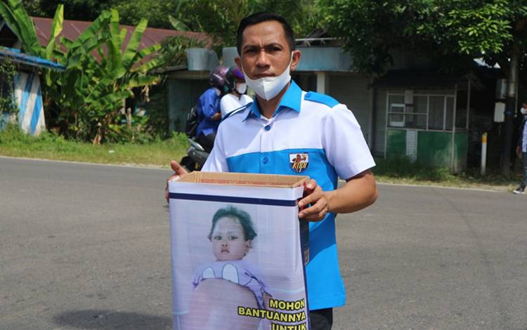 Ketua KNPI Katingan Budy Hermanto memegang gambar bocah penderita pembengkakan perut saat penggalangan dana.
