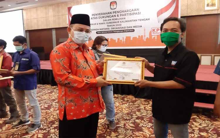 Ketua KPU Kalteng, Harmain Ibrohim menyerahkan piagam penghargaan kepada Borneonews.co.id, Jumat 9 April 2021