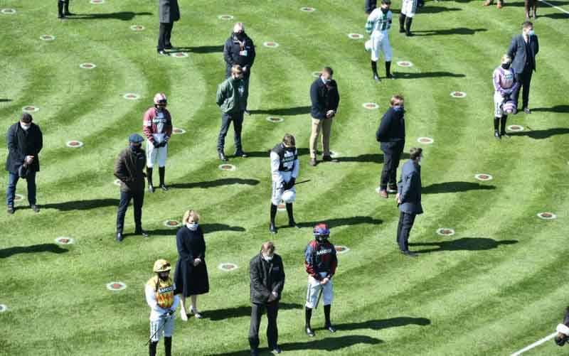 Sejumlah joki dan pelatih melakukan hening selama satu menit menyusul pengumuman kematian Pangeran Philip, Duke of Edinburg, di Grand National Festival, Aintree Racecourse, Liverpool. (9/4/2021) (foto : AFP/Pool/Peter Powell)