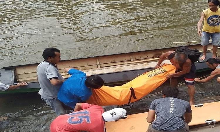 Sejumlah warga dan aparat mengevakuasi korban yang ditemukan tewas di tepi sungai.