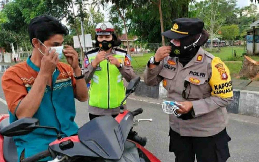 Polwan Polres Kapuas membagikan masker kepada pengendara melintas di Jalan Tambun Bungai, Kuala Kapuas