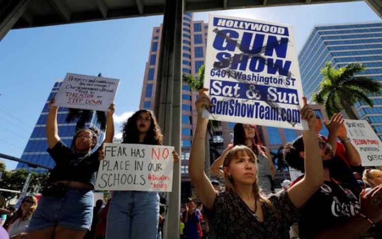 Seorang pemrotes membawa spanduk dalam sebuah aksi mengenai pengendalian senjata lebih lanjut, tiga hari setelah terjadi penembakan di Sekolah Marjory Stoneman Douglas, di Fort Lauderdale, Florida, Amerika Serikat, Sabtu (17/2/2018)