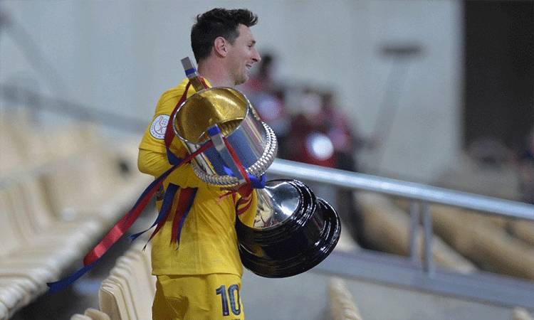 Pemain Barcelona Lionel Messi memegang trofi Copa del Rey setelah mengalahkan Athletic Club Bilbao dalam partai final di Stadion La Cartuja di Seville pada 17 April 2021. (AFP/CRISTINA QUICLER)