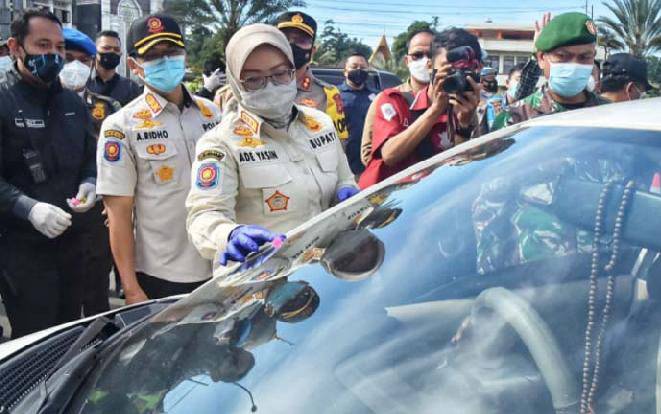 Bupati Bogor Ade Yasin menempelkan stiker berwarna hijau pada kendaraan yang boleh masuk ke wilayah Kabupaten Bogor pada libur Imlek, Jumat 12 Februari 2021. (Foto: Antaranews)