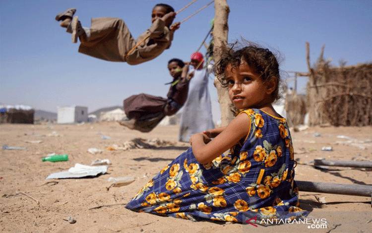 Seorang anak perempuan duduk saat anak lainnya bermain ayunan di sebuah kamp pengungsi di Marib, Yaman, Selasa (16/2/2021). ANTARA FOTO/REUTERS/Nabeel al-Awzari/WSJ/cfo