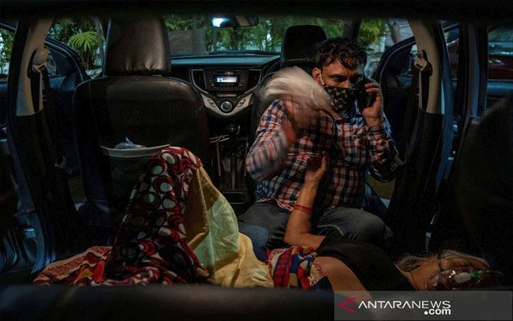 Manoj Kumar duduk di sebelah ibunya, Vidhya Devi, yang menderita kesulitan bernapas, ketika menerima bantuan oksigen secara gratis di dalam mobilnya d Gurudwara (kuil Sikh) di Ghaziabad, India, Sabtu (24/4/2021), saat virus corona (COVID-19) mewabah. REUTERS/Danish Siddiqui/AWW/djo