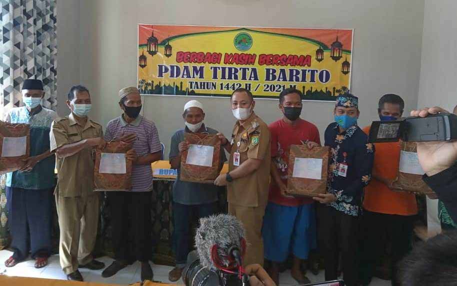 Bupati Barsel, Eddy Raya Samsuri dan Direktur PDAM Tirta Barito Buntok, Rona Cipta menyerahkan sembako kepada warga