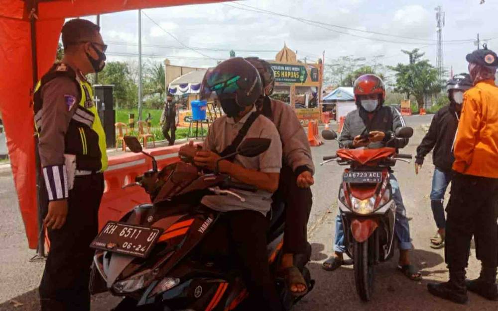 Petugas saat memeriksa dokumen warga yang ingin melintas di pos penyekatan arus mudik perbatasan Kalteng - Kalsel di Jalan Trans Kalimantan Km 12,5 Kecamatan Kapuas Timur pada Kamis, 6 Mei 2021.