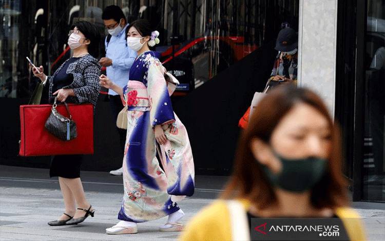 Seorang wanita dalam balutan kimono berjalan dengan menggunakan masker, di sebuah distrik perbelanjaan pada hari pertama keadaan darurat ketiga negara itu, ditengah wabah virus corona (COVID-19), di Tokyo, Jepang, Minggu (25/4/2021). REUTERS/Kim Kyung-Hoon/AWW/djo (REUTERS/KIM KYUNG-HOON)