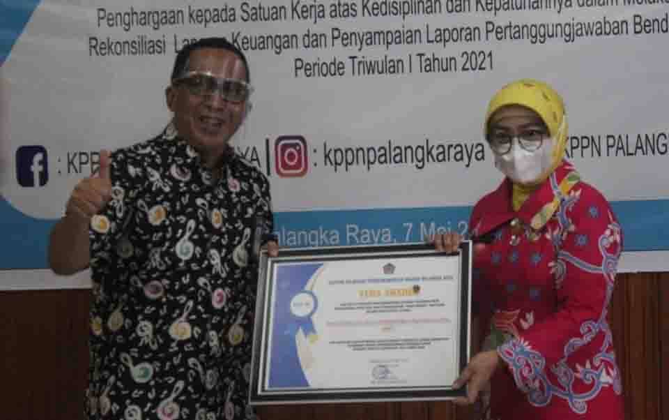 Kepala KPPN Palangka Raya Muhtar Salim menyerahkan penghargaan kepada Kepala Disdagperin Kalteng Aster Bonawaty, di Aula KPPN Palangka Raya, Jumat 7 Mei 2021. (Foto:Agung)
