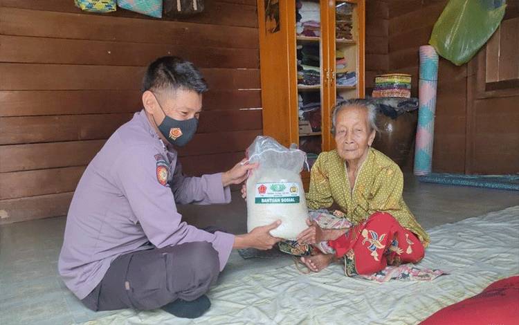 Personel Polsek Hanau saat menyerahkan beras kepada salah satu warga di Desa Pembuang Hulu