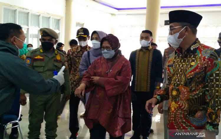 Menteri Sosial Republik Indonesia Tri Rismaharini didampingi Bupati Solok Selatan Khairunas mengukur suhu tubuh sebelum menyerahkan bantuan bagi korban tanah longsor di Kabupaten itu, Rabu (12/5/2021)