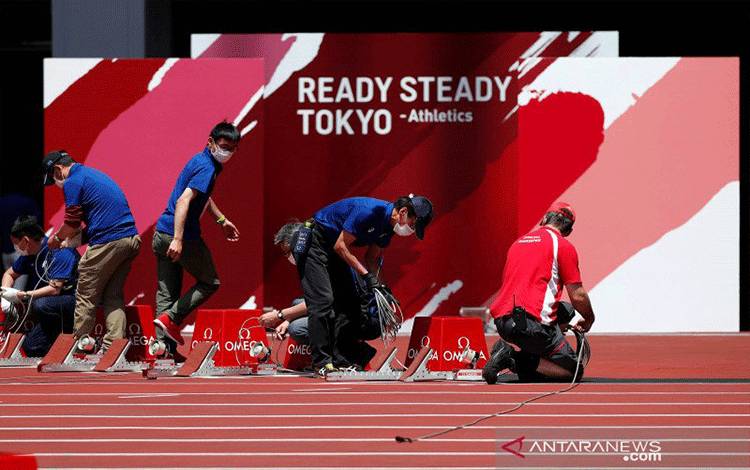Sejumlah ofisial menyiapkan perlengkapan dalam uji coba pelaksanaan pertandingan atletik untuk Olimpiade Tokyo di Olympic Stadium, Tokyo, Jepang, Minggu (9/5/2021). Uji coba atletik Olimpiade digelar tanpa penonton. ANTARA FOTO/REUTERS/Issei Kato/foc.