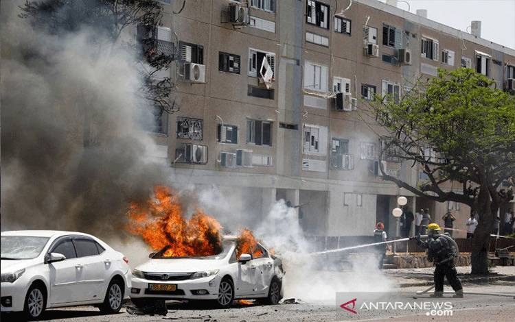 Petugas pemadam kebakaran Israel memadamkan mobil yang terbakar, setelah sebuah roket diluncurkan dari Jalur Gaza, di Ashkelon, Israel selatan, Selasa (11/5/2021). ANTARA FOTO/REUTERS/Nir Elias/FOC/sa.