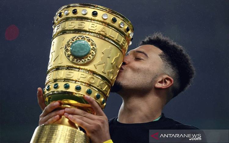 Penyerang sayap Borussia Dortmund Jadon Sancho mencium trofi Piala DFB Pokal yang ia raih bersama rekan-rekannya seusai mengalahkan RB Leipzig dalam partai final musim 2020/21 di Olympiastadion, Berlin, Jerman, Kamis (13/5/2021) waktu setempat. (ANTARA/REUTERS/POOL/Martin Rose)