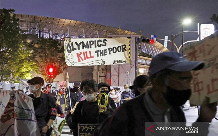 Orang-orang memprotes penyelenggaraan Olimpiade Tokyo 2020, di tengah wabah penyakit virus corona (COVID-19), di sekitar Stadion Olimpiade (Stadion Nasional) saat acara uji coba atletik Olimpiade diadakan di dalam venue di Tokyo, Jepang, Minggu (9/5/2021), foto ini diambil oleh Kyodo. Kyodo/via REUTERS/AWW/sa. (REUTERS/KYODO)